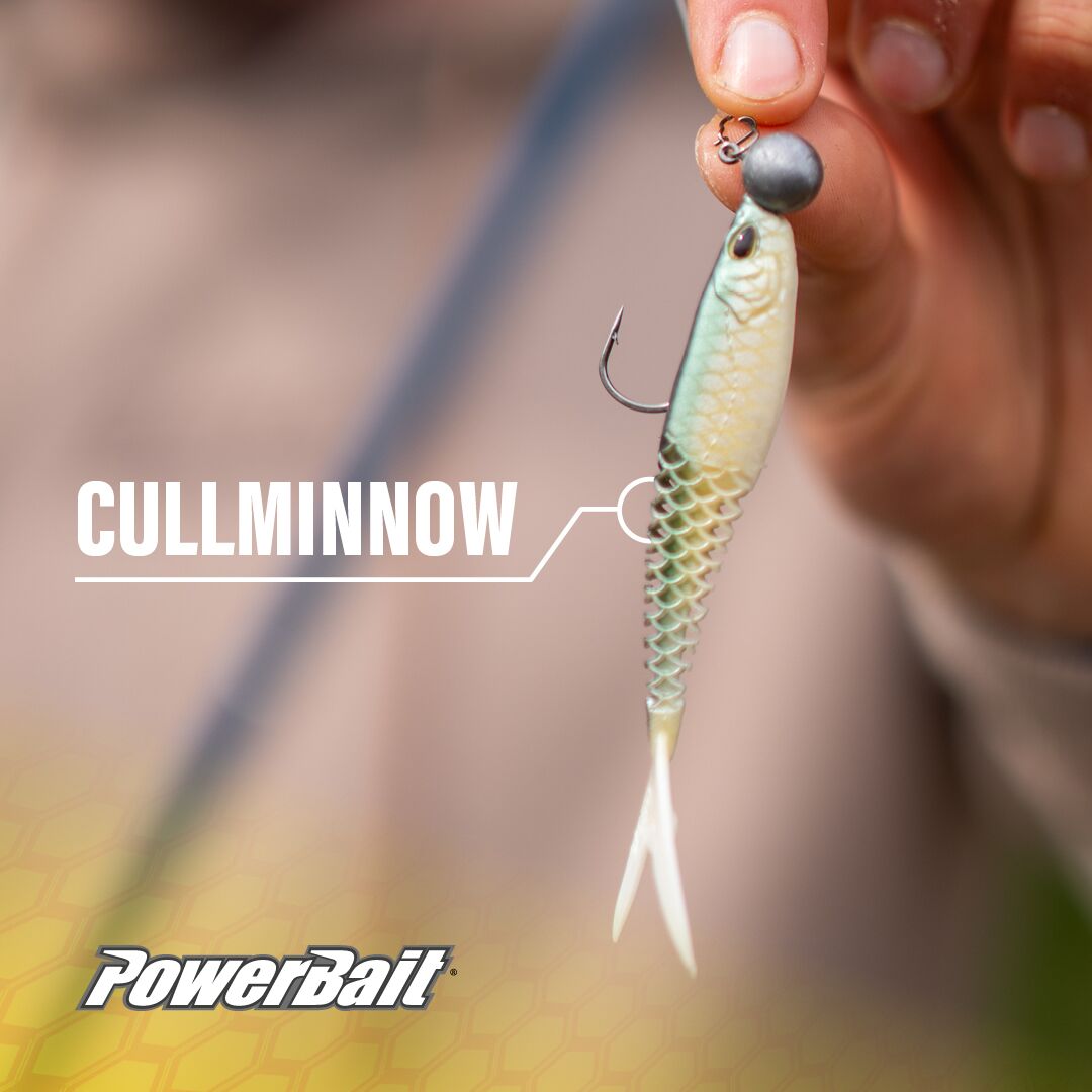 An out of focus background with little detail. A hand, in focus, holding a small white and silvery metallic green softbait by the ball-jig out towards the camera.
The softbait has a white line coming off it with the title above CULLMINNOW. In the bottom left of the image there's a PowerBait text logo for Berkley, above a transparent yellow honeycomb pattern.